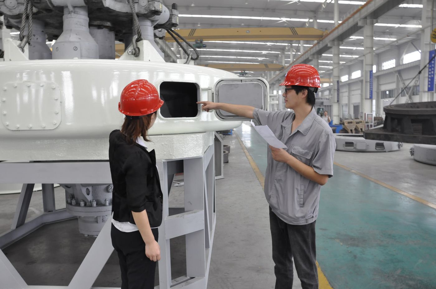 Two workers checking a mill on the shop floor during assembly.